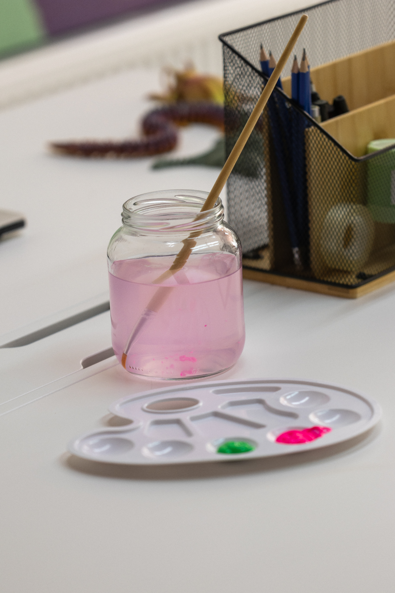 Waterpotje met een penseel en een palet met verf op een werktafel in het atelier.